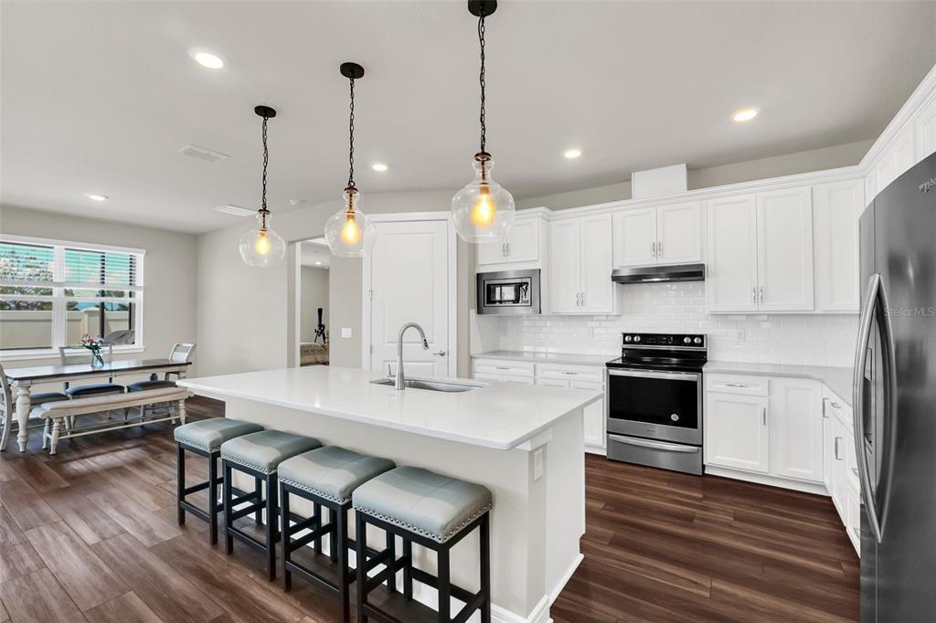 2001 Spring Shower Circle Kissimmee, FL 34744 - Photo 6 of 25 a kitchen with stainless steel appliances kitchen island granite countertop a stove a sink a oven a refrigerator and white cabinets with wooden floor