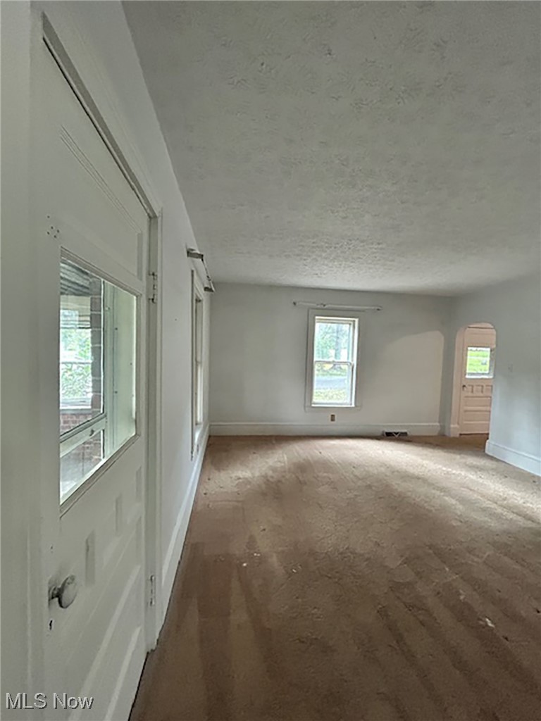 6128 Riverview Road Peninsula, OH 44264 - Photo 7 of 17 Carpeted empty room with plenty of natural light, arched walkways, and a textured ceiling