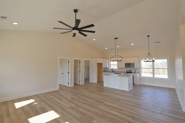 a open kitchen with a refrigerator a sink and a wooden floor