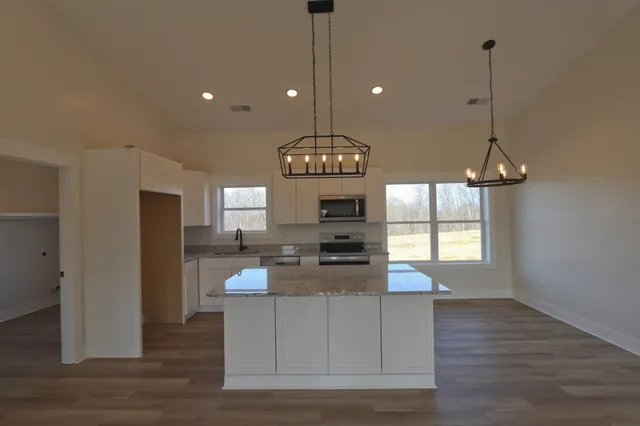 a kitchen with stainless steel appliances granite countertop a stove and a wooden floor