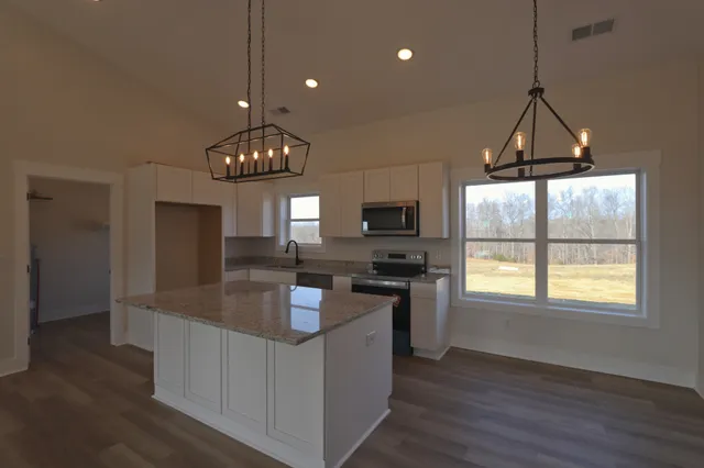 a kitchen with granite countertop a stove a sink a refrigerator dining table and chairs