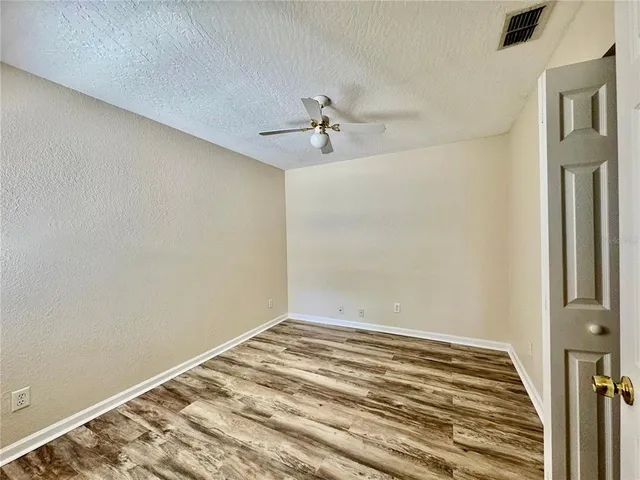 a view of a room with wooden floor and a ceiling fan