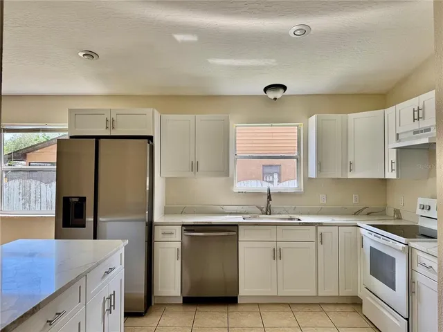 a kitchen with granite countertop white cabinets white stainless steel appliances and sink