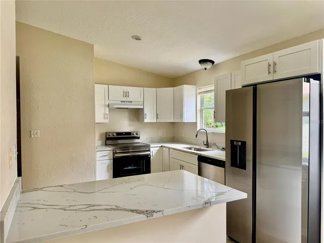 a kitchen with stainless steel appliances granite countertop a sink stove and refrigerator