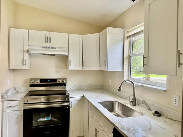 a kitchen with granite countertop a sink a stove and cabinets