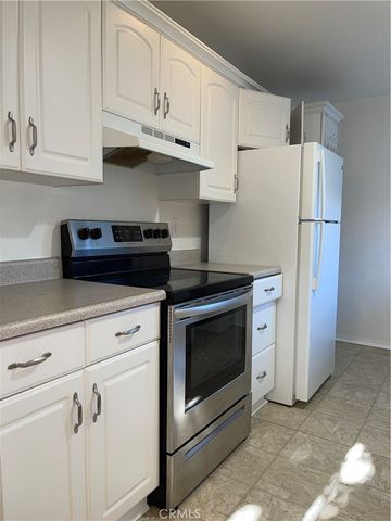 a kitchen with stainless steel appliances white cabinets and a stove a refrigerator with white cabinets