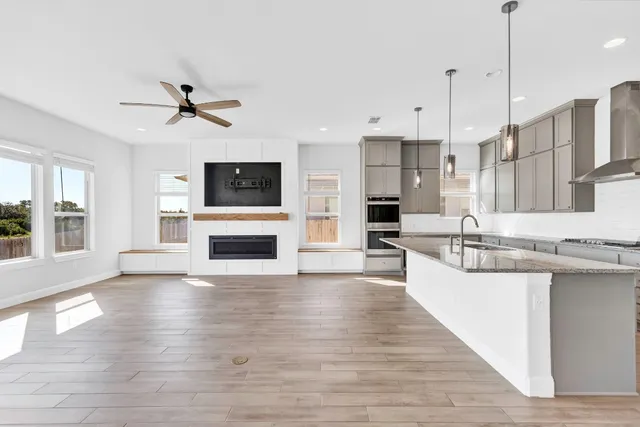 a view of a kitchen with kitchen island a large counter top space a sink stainless steel appliances and a window