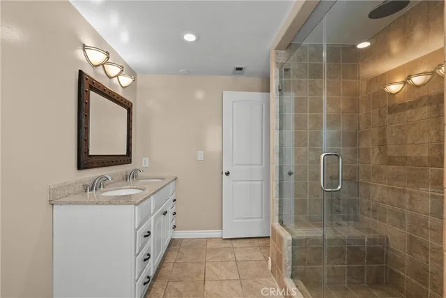 a bathroom with a double vanity sink mirror and shower