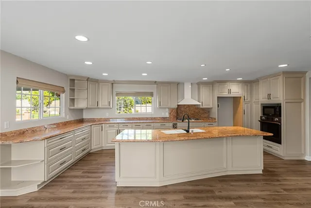 a large kitchen with stainless steel appliances kitchen island granite countertop a large cabinets a sink and a stove
