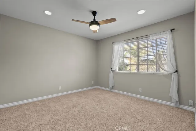 an empty room with ceiling fan and windows