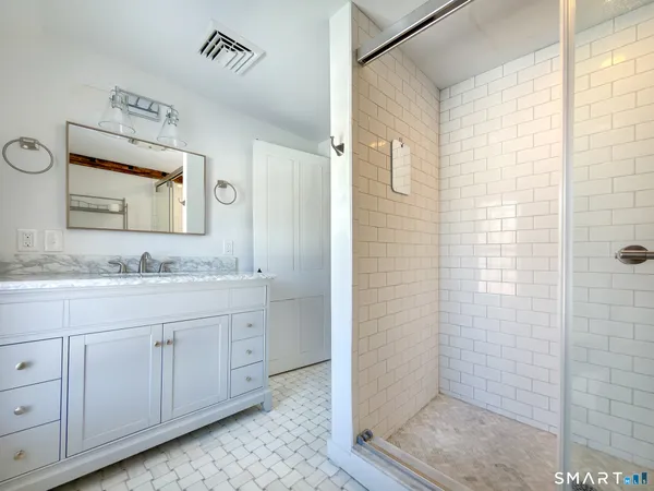 a bathroom with a granite countertop sink a mirror and shower