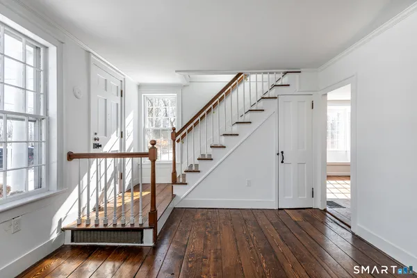 an empty room with wooden floor fireplace and windows