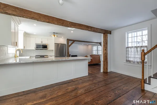 a large white kitchen with wooden floor and a window