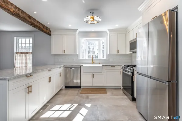 a kitchen with white cabinets stainless steel appliances and window