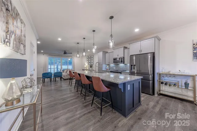 a kitchen with stainless steel appliances granite countertop a refrigerator a sink dishwasher a stove and white cabinets with wooden floor