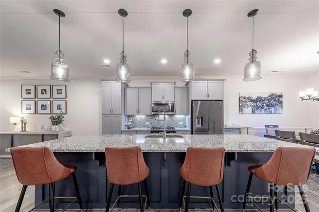 a kitchen with granite countertop a dining table chairs and white cabinets