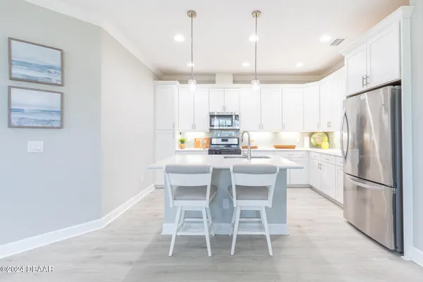 a kitchen that has a lot of white cabinets and stainless steel appliances
