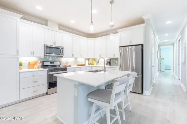a kitchen with a sink a stove a refrigerator and white cabinets