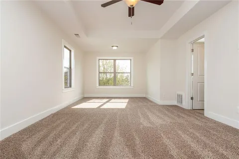 an empty room with chandelier fan and windows