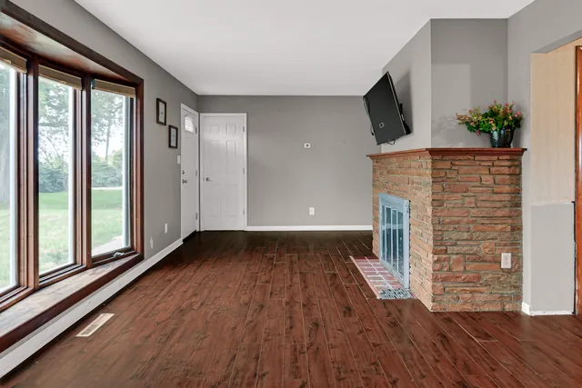 a view of empty room with wooden floor and fireplace
