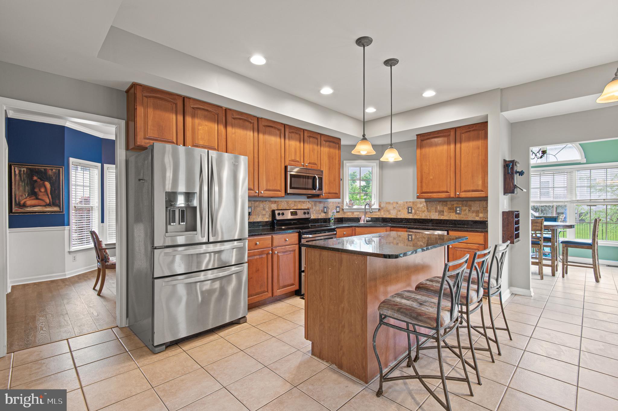 985 Silver Maple Circle Seven Valleys, PA 17360 - Photo 11 of 50 a kitchen with granite countertop a refrigerator a stove a sink and a dining table
