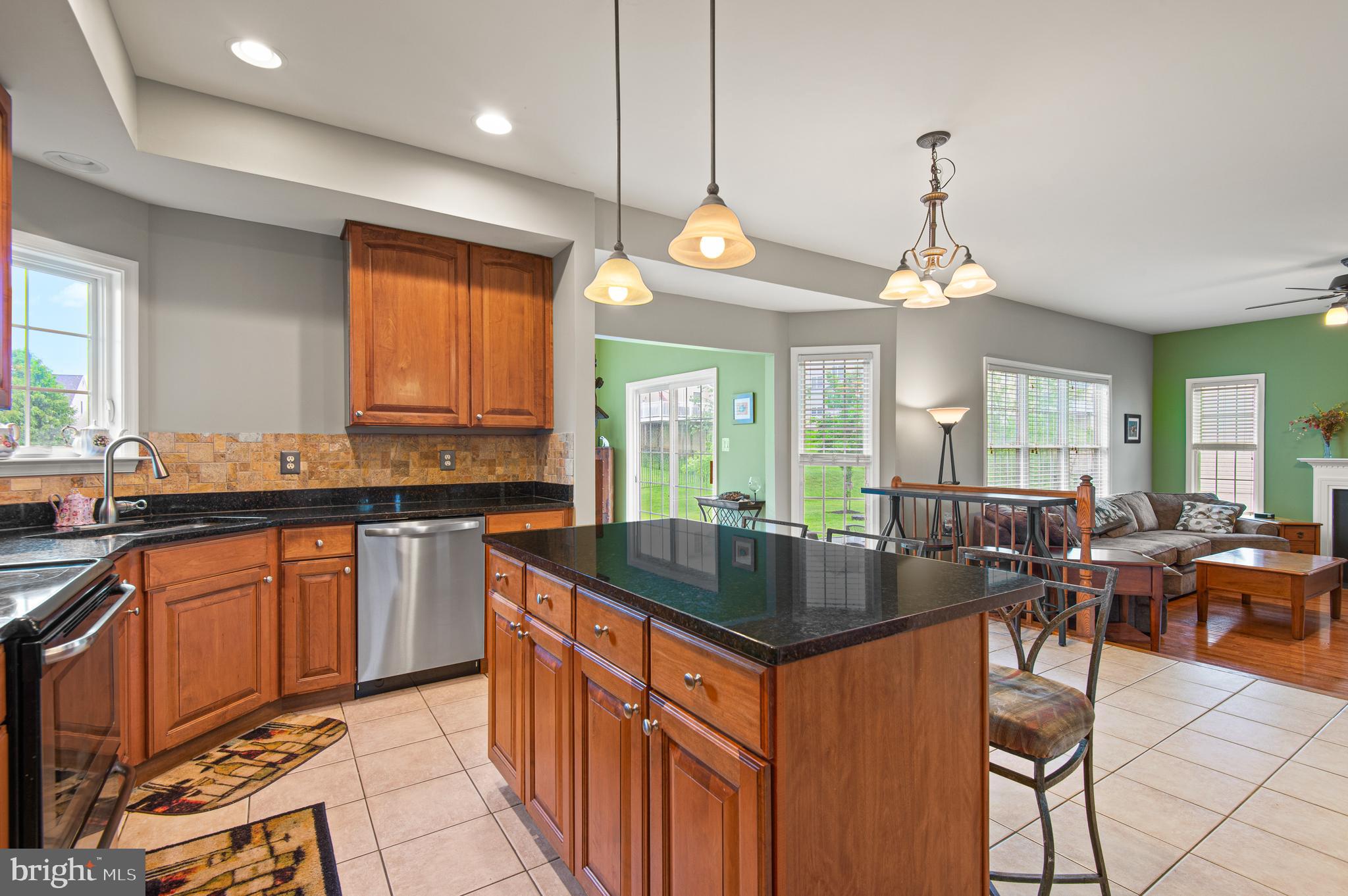 985 Silver Maple Circle Seven Valleys, PA 17360 - Photo 8 of 50 a kitchen with granite countertop a stove a sink a center island a dining table and chairs