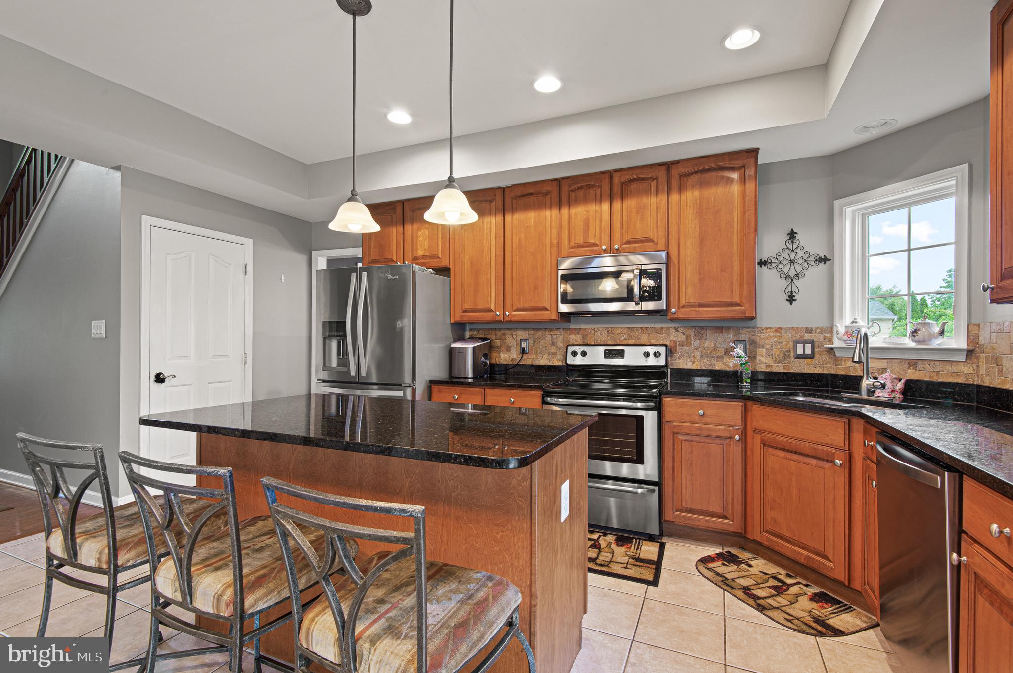 985 Silver Maple Circle Seven Valleys, PA 17360 - Photo 9 of 50 a kitchen with stainless steel appliances granite countertop a stove top oven a sink dishwasher a dining table and chairs with wooden floor