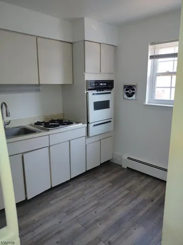 a kitchen with stainless steel appliances a white stove top oven cabinets and a wooden floor