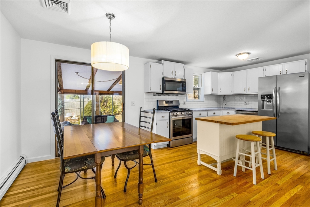 64 McNamara Road Yarmouth, MA 02673 - Photo 4 of 28 a kitchen with stainless steel appliances granite countertop a stove a refrigerator a kitchen island a dining table and chairs with wooden floor