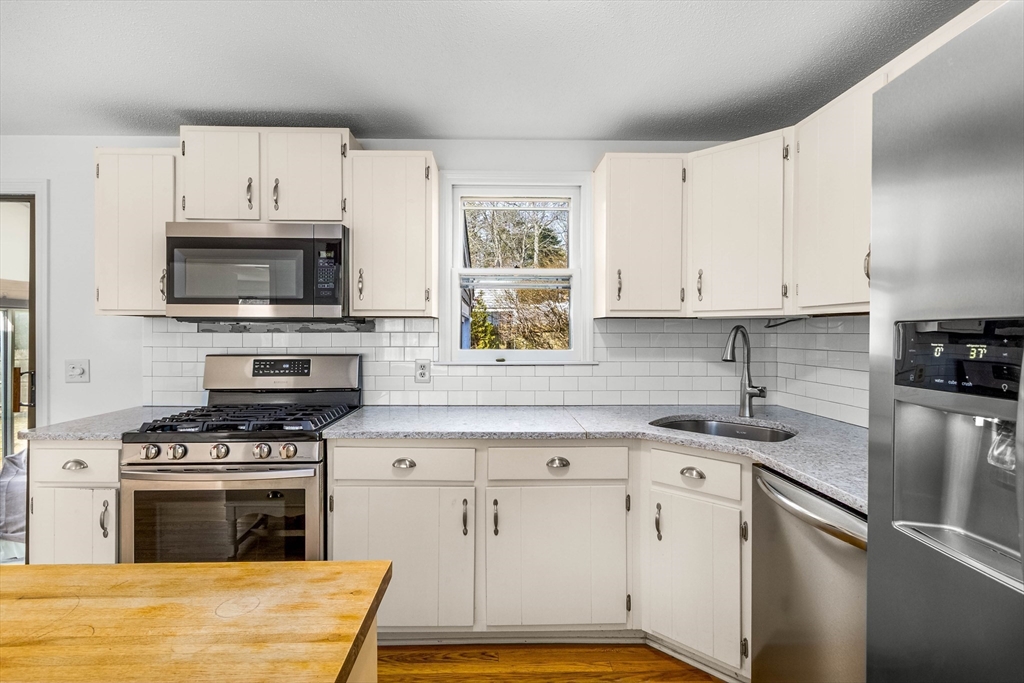 64 McNamara Road Yarmouth, MA 02673 - Photo 5 of 28 a kitchen with granite countertop a stove a sink and a microwave