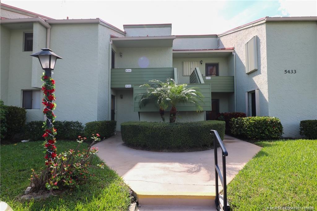 5433 Southeast Miles Grant Road, Unit 203 Stuart, FL 34997 - Photo 1 of 15 a front view of a house with a yard