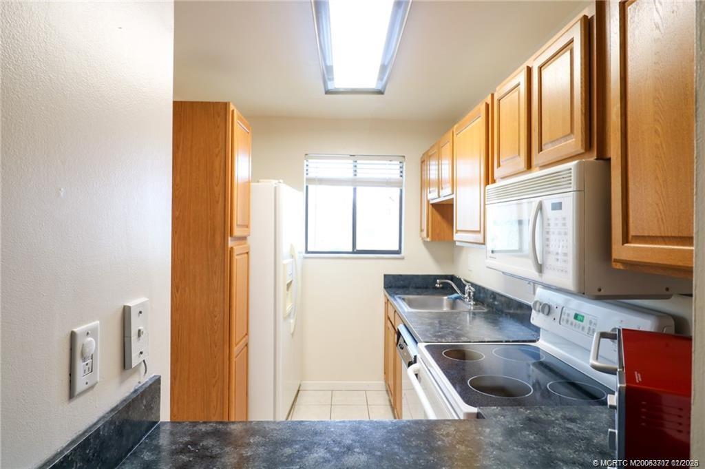 5433 Southeast Miles Grant Road, Unit 203 Stuart, FL 34997 - Photo 2 of 15 a kitchen with stainless steel appliances granite countertop a sink and a refrigerator