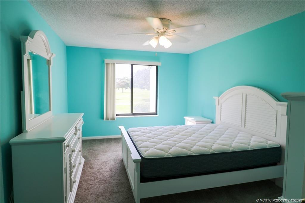5433 Southeast Miles Grant Road, Unit 203 Stuart, FL 34997 - Photo 8 of 15 a bedroom with a bed and a chandelier