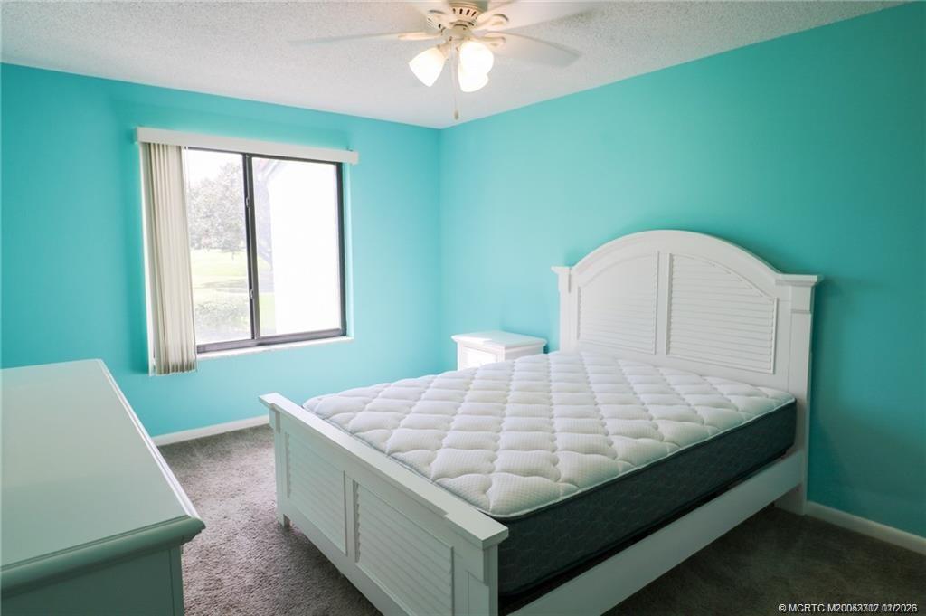 5433 Southeast Miles Grant Road, Unit 203 Stuart, FL 34997 - Photo 9 of 15 a bed sitting in a bedroom next to a window