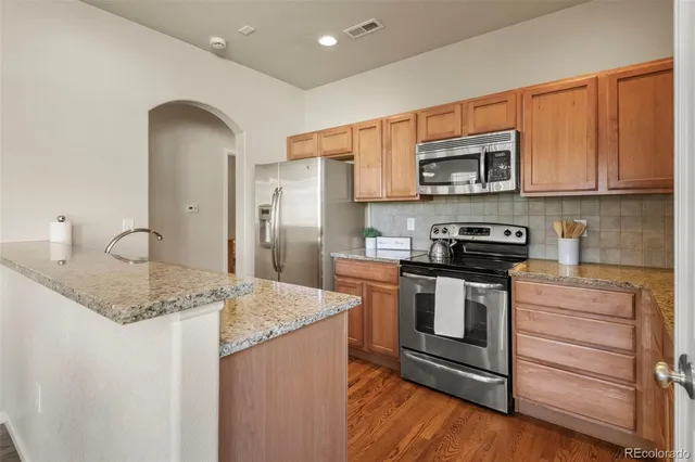 a kitchen with stainless steel appliances granite countertop a stove a sink and a refrigerator