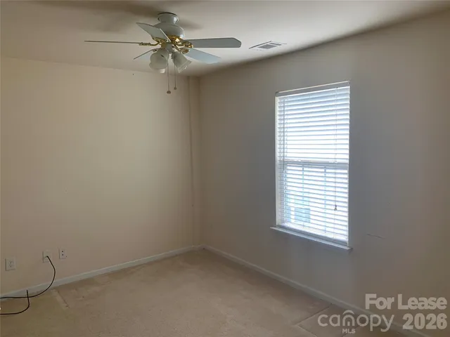 an empty room with a window and a fan