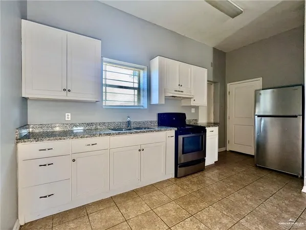 a kitchen with granite countertop a refrigerator sink and cabinets