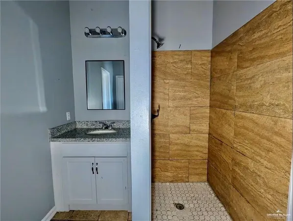 a bathroom with a granite countertop sink a mirror and shower