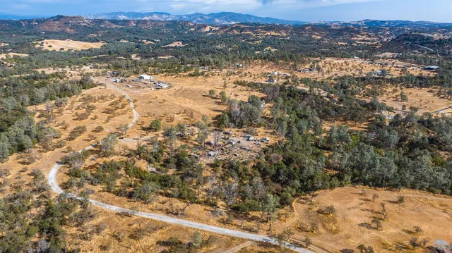 an aerial view of house with yard and mountain view in back