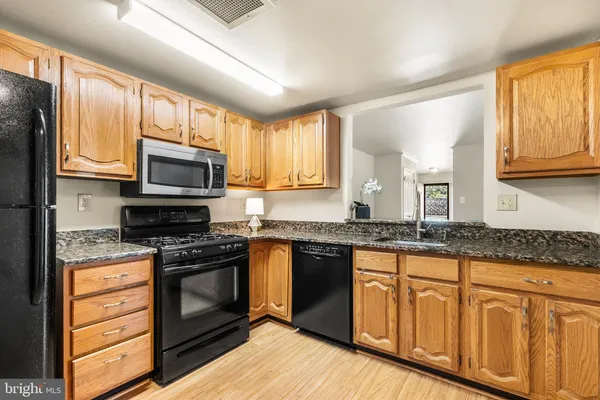 a kitchen with granite countertop wooden cabinets stainless steel appliances and a window
