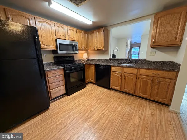 a kitchen with stainless steel appliances granite countertop a stove a sink dishwasher and a refrigerator with wooden floor