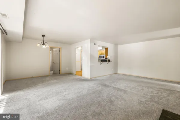 an empty room with chandelier fan and windows