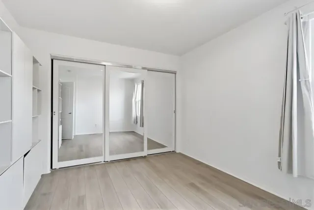 a view of empty room with wooden floor and entryway