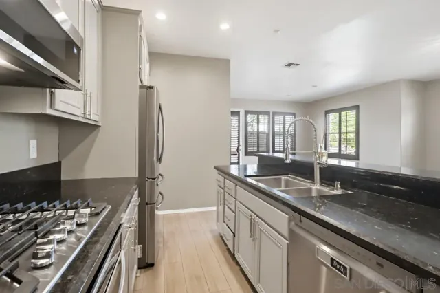 a kitchen with granite countertop a sink stove and refrigerator