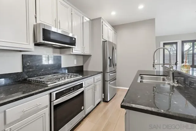 a kitchen with stainless steel appliances granite countertop a sink stove and refrigerator
