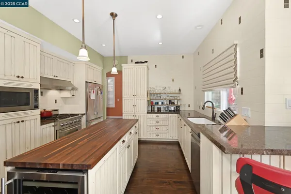 a kitchen with stainless steel appliances a stove top oven a sink dishwasher and a refrigerator with wooden floor