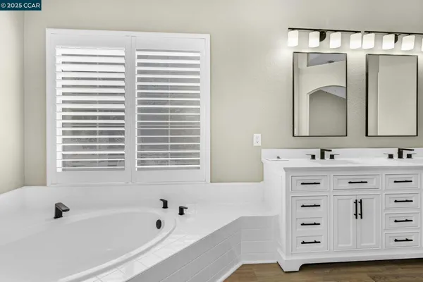 a bathroom with a bathtub a double vanity sink and mirror