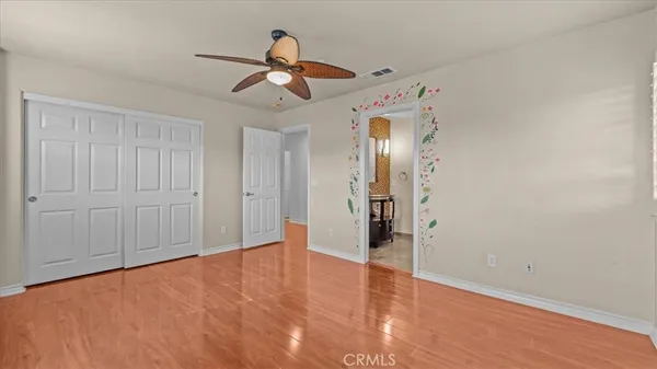 a view of empty room with wooden floor and ceiling fan