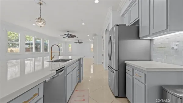 a kitchen with a sink stainless steel appliances a counter top space cabinets and a chandelier