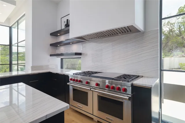 a kitchen with stainless steel appliances kitchen island granite countertop a table chairs in it and wooden floors